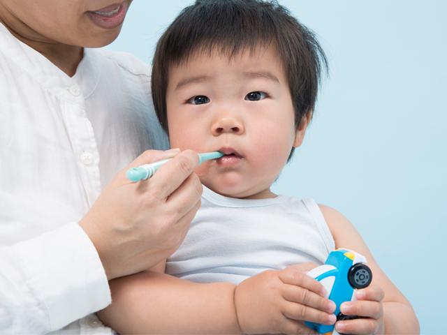 お子様の歯磨きを行う親