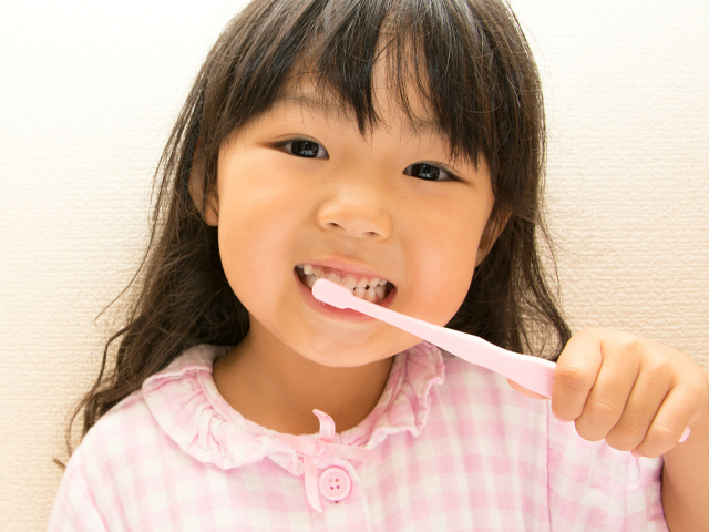 お子様の仕上げ磨きをする母親