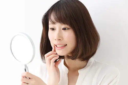 鏡で歯を確認する女性