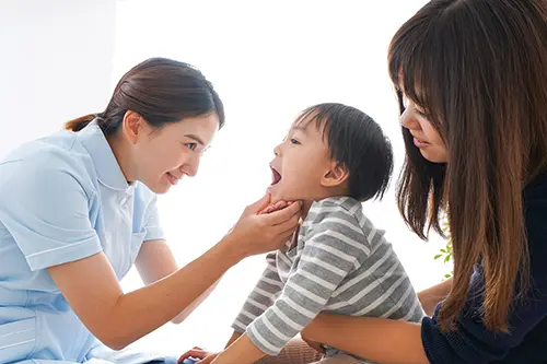 子供の口腔内をチェックする歯科医師