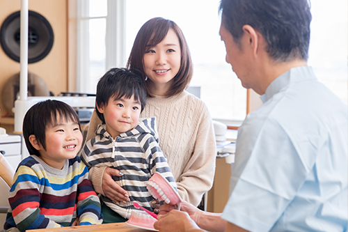 小児歯科の診療室で歯科医師と話す子どもと保護者