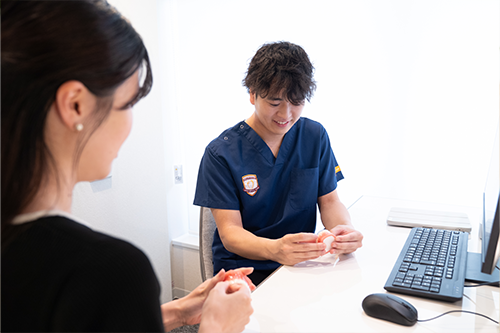 歯の模型で歯並びについて説明する歯科医師