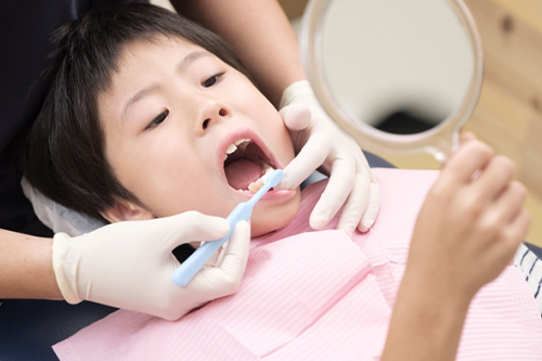 鏡で口腔内を確認する子どもと歯科衛生士